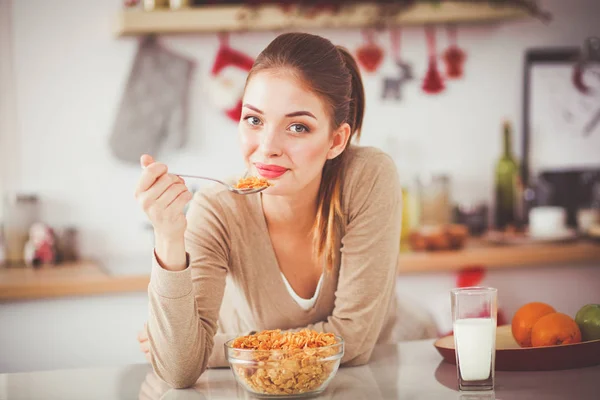 Ler attraktiv kvinna äter frukost i köket interiör. Leende kvinna attraktiv. — Stockfoto