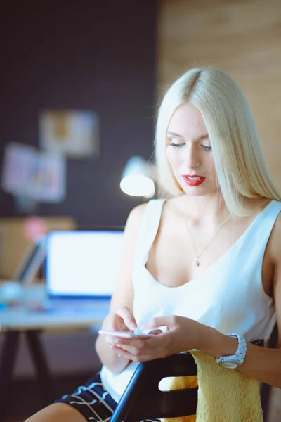 Woman designer using on mobile phone in office