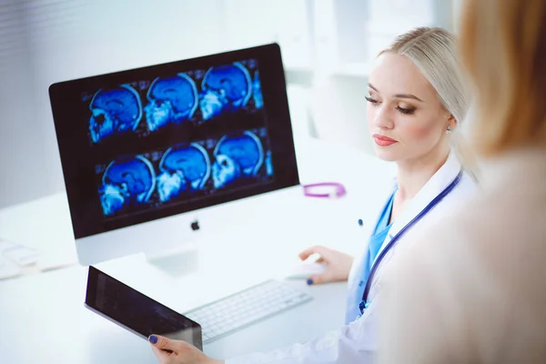 Dokter en patiënt bespreken iets terwijl ze aan tafel zitten. Geneeskunde en gezondheidszorg. Dokter en patiënt — Stockfoto