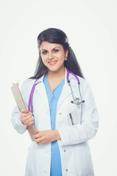 Médico joven con portapapeles y estetoscopio de pie sobre fondo blanco — Foto de Stock