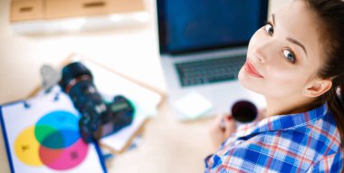 Masada dizüstü bilgisayarla oturan kadın fotoğrafçı.