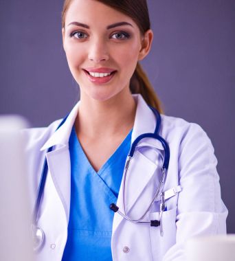 Gri arka planda oturan kadın doktor