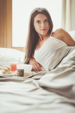 bir bardak süt ile yatakta oturan genç kadın