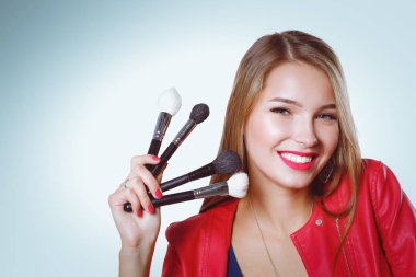 Genç güzel kadın elinde makyaj için fırça tutar .