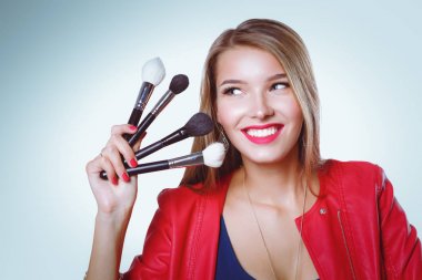 Genç güzel kadın elinde makyaj için fırça tutar .