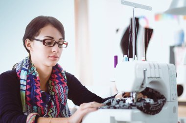 Çalışırken dikiş diken genç bir kadın. .