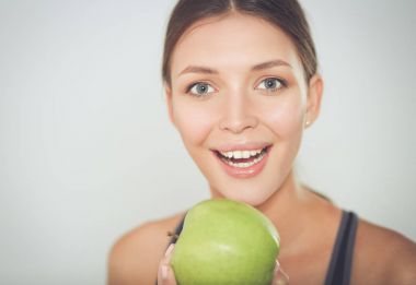 Mutlu genç kadın elma yiyor, beyaz arka planda soyutlanmış..