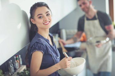 Bir çift evdeki mutfaklarında birlikte yemek pişiriyor.