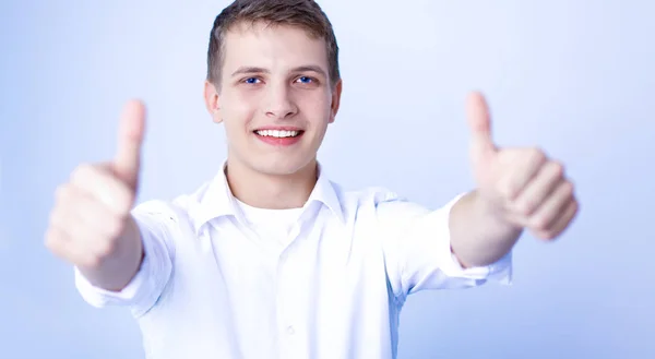 Retrato de un joven sonriendo sentado sobre un fondo gris — Foto de Stock