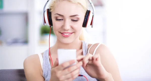 Junge schöne Frau sitzt zu Hause auf dem Sofa und hört Musik — Stockfoto