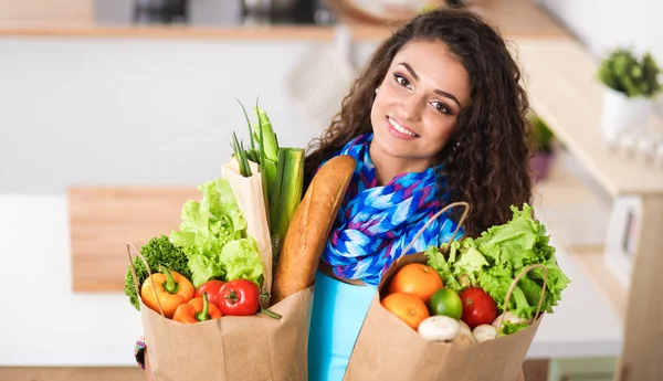 Giovane donna che tiene la spesa con verdure In piedi in cucina. — Foto Stock