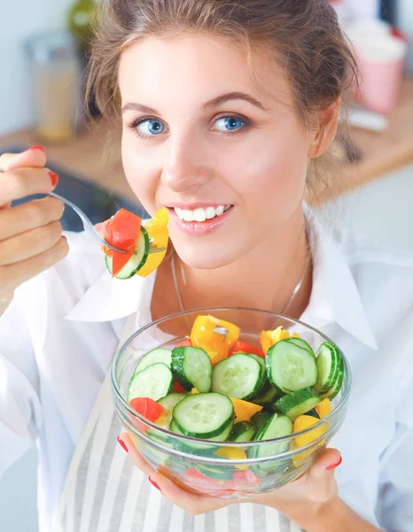 Mujer joven comiendo ensalada fresca en la cocina moderna — Foto de Stock