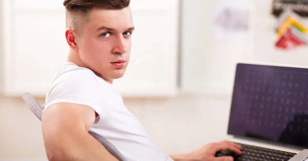 Young man sitting on chair with laptop — Stock Photo, Image