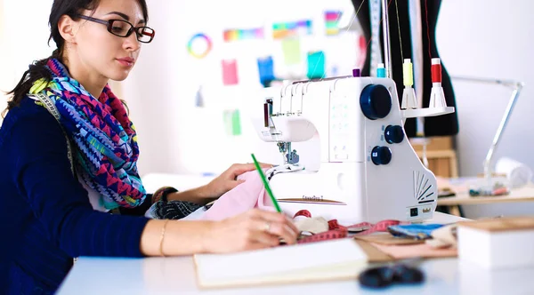 Mujer joven cosiendo sentado en su lugar de trabajo — Foto de Stock