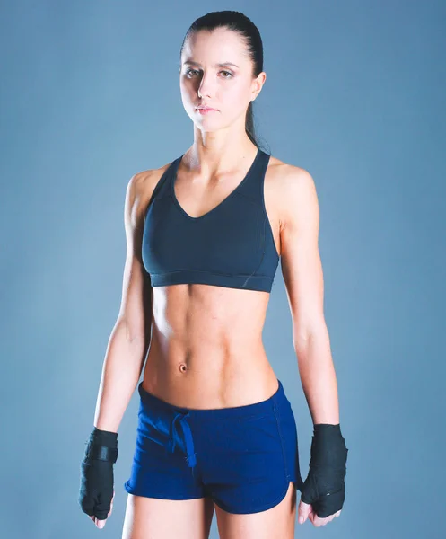 Muscular young woman posing in sportswear against black background. — Stock Photo, Image