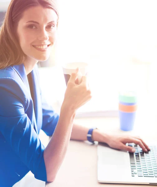 Aantrekkelijke Glimlachende zakenvrouw zitten op kantoor, houden van een kopje koffie — Stockfoto