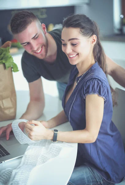 Pareja pagando sus cuentas con el ordenador portátil en la cocina en casa — Foto de Stock