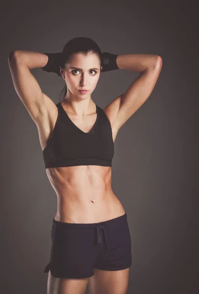 Muscular young woman posing in sportswear against black background — Stock Photo, Image