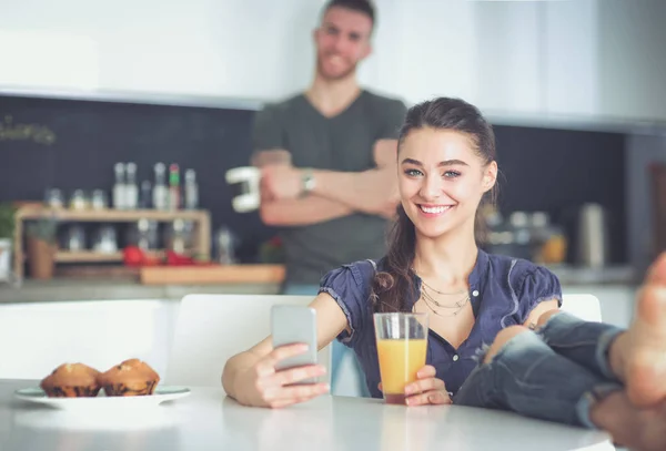 Lyckliga par med smartphone som sitter i köket — Stockfoto