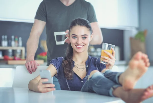 Pareja feliz usando smartphone sentado en la cocina —  Fotos de Stock