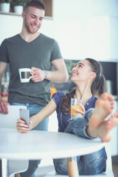 Pareja feliz usando smartphone sentado en la cocina — Foto de Stock