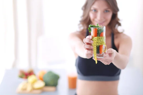 Mulher segurando um copo cheio de salada de frutas frescas com uma fita métrica ao redor do copo. — Fotografia de Stock