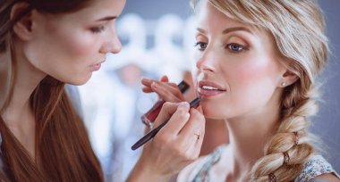 Kadından profesyonel makyaj yapan sanatçı.