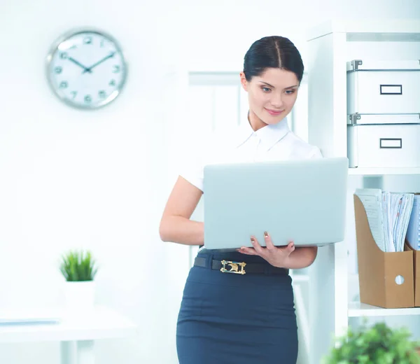 Attraktiva affärskvinna står i office med laptop — Stockfoto