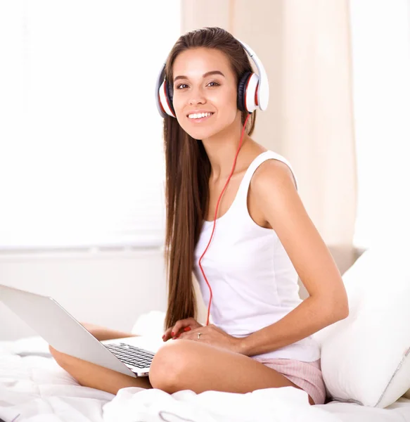Joven hermosa mujer en la cama escuchando música — Foto de Stock