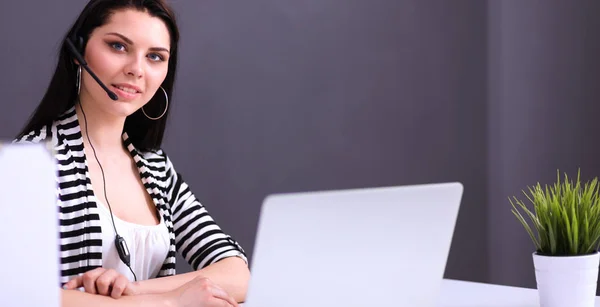 Mulher de negócios bonita trabalhando em sua mesa com fone de ouvido e laptop — Fotografia de Stock