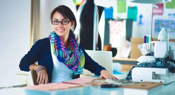 Beautiful fashion designer sitting at the desk in studio — Stock Photo, Image