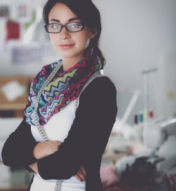 Güzel genç moda tasarımcısı stüdyoda duruyor.