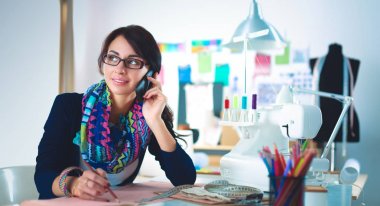 Genç terzi kâğıt üzerinde kıyafet deseni tasarlıyor.