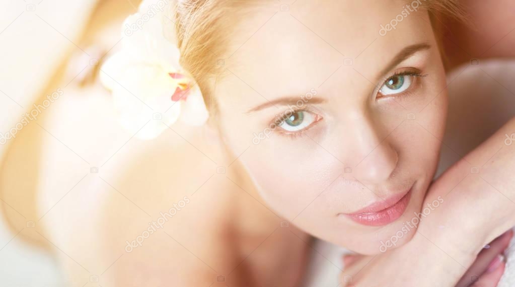 Beautiful young woman getting spa massage, lying on salon