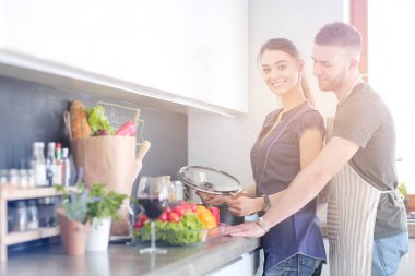 Bir çift evdeki mutfaklarında birlikte yemek pişiriyor.