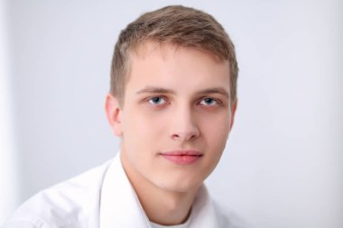 Gri arka plan üzerinde oturan gülümseyen genç adam portresi. Genç adam portresi