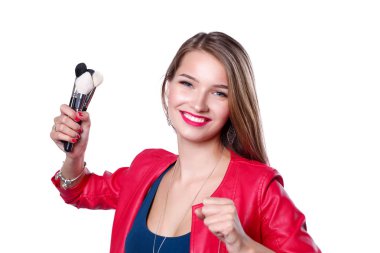 Genç ve güzel bir kadın bir elinde makyaj için boya ve gölgeli bir palet, makyaj için ikinci el fırça..