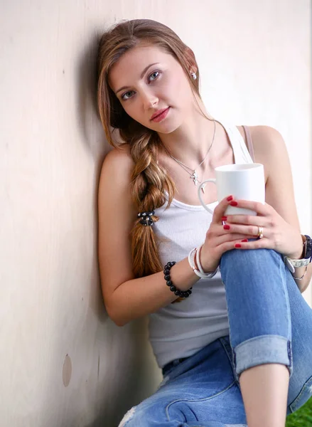 Hermosa mujer sentada en el suelo y sosteniendo una taza. Hermosa mujer —  Fotos de Stock