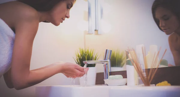 Jeune femme se lave le visage avec de l'eau propre dans la salle de bain — Photo