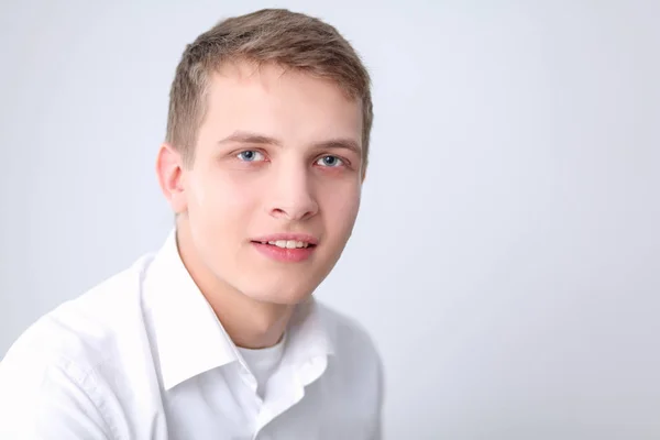 Portret van de jonge man die lacht zittend op een grijze achtergrond. Portret van jonge man — Stockfoto