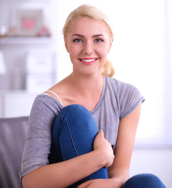 Jonge mooie vrouw zitten op de bank in haar kamer — Stockfoto