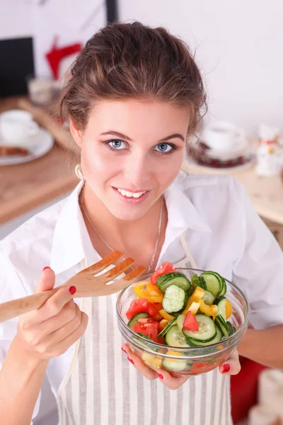 Mujer joven sonriente preparando ensalada en la cocina . — Foto de Stock