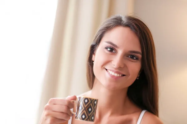 Mujer joven sentada en la cama con una taza de leche —  Fotos de Stock