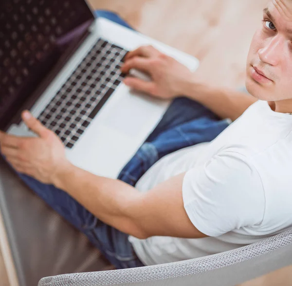 Young man sitting on chair with laptop — Stock Photo, Image