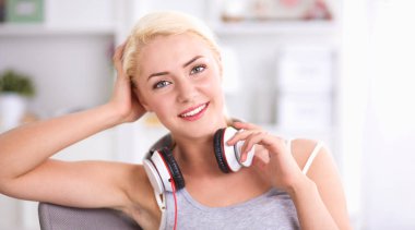 Evdeki genç ve güzel kadın kanepede oturup müzik dinliyor.