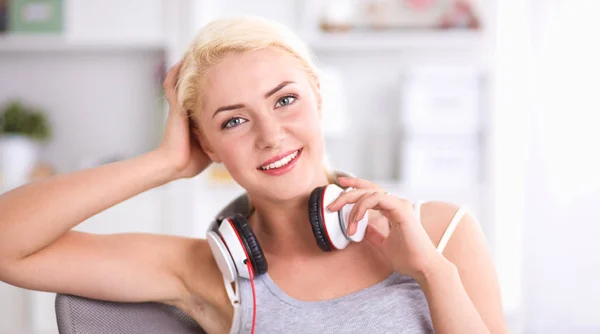 Jonge mooie vrouw thuis zitten op de bank en luisteren muziek — Stockfoto