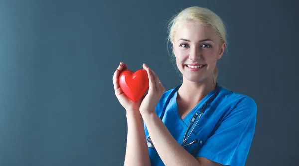 Doctor with stethoscope holding heart, isolated on grey background — Stock Photo, Image