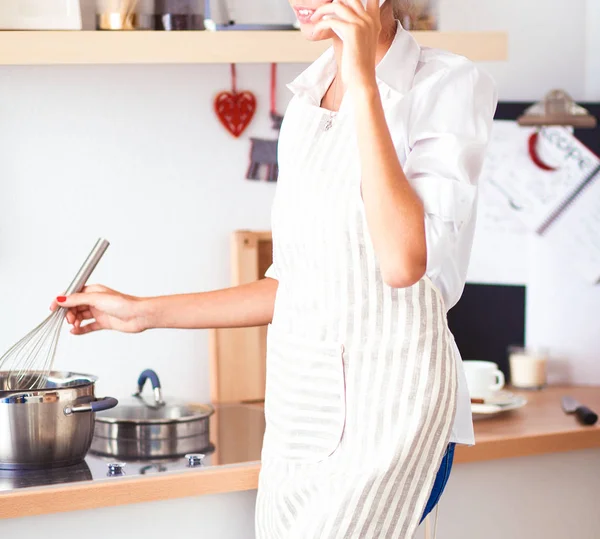 Porträtt en leende kvinna med telefon i köket hemma — Stockfoto