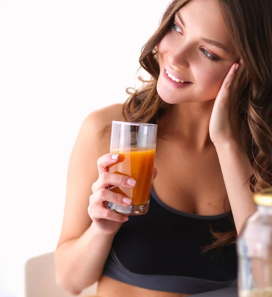 Menina sentada na cozinha na mesa com suco de frutas e copos — Fotografia de Stock