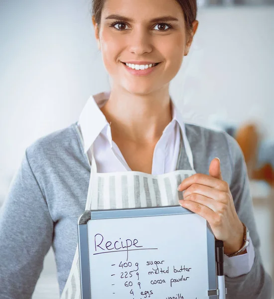 Kvinna i köket hemma, stående nära skrivbord med mapp — Stockfoto